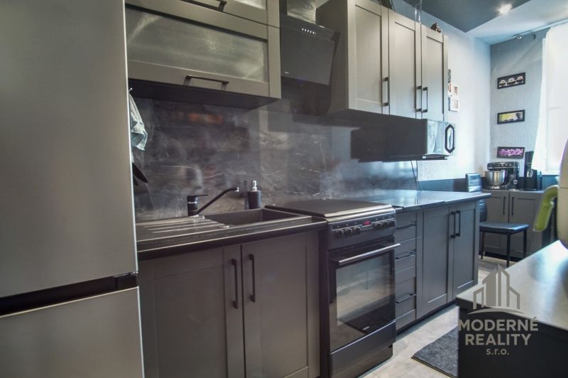 A kitchen in a 3-room apartment with gray cabinets and black appliances.