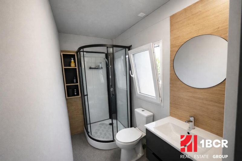Bathroom in a holiday apartment with a modern shower and a mirrored wall.