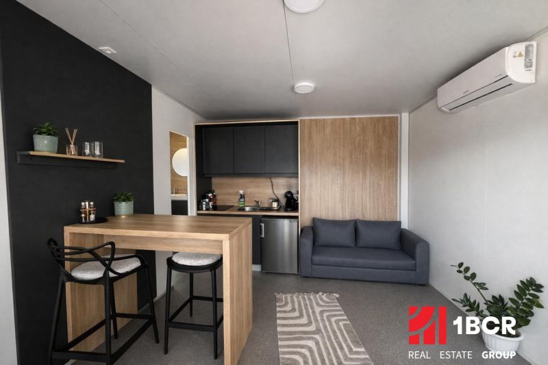 Recreational apartment with wood-decor flooring, kitchenette, and sofa.
