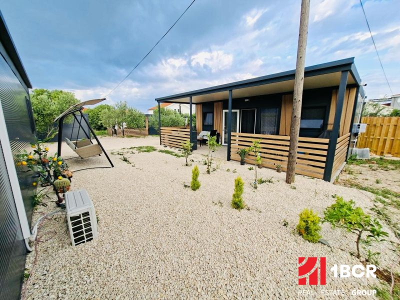 A recreational apartment in Sukošan with a terrace, gravel yard, and a swing bench.