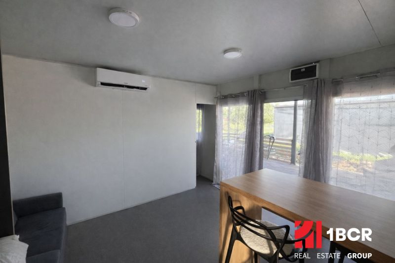 Interior of a holiday apartment with a sofa and wall-mounted air conditioning, light fixtures, and a table.