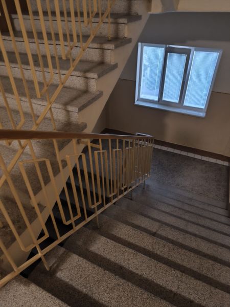 A hallway with a staircase in a 3-room apartment, with a window and a railing.