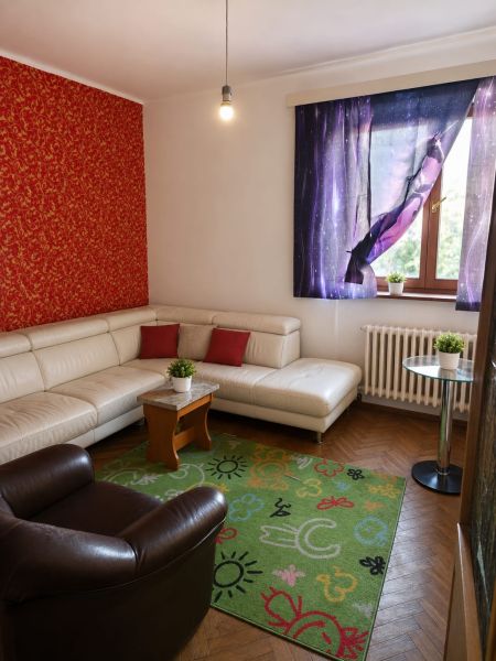 Living room with a sofa, colorful rug, and wood-patterned flooring in a three-room apartment.
