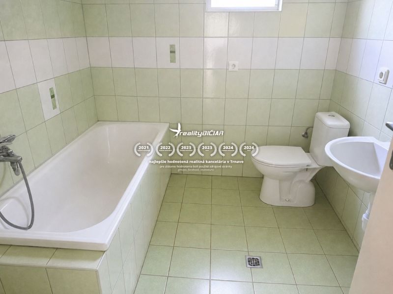 Bathroom in a family house with a bathtub and toilet, tiled with pastel tiles.