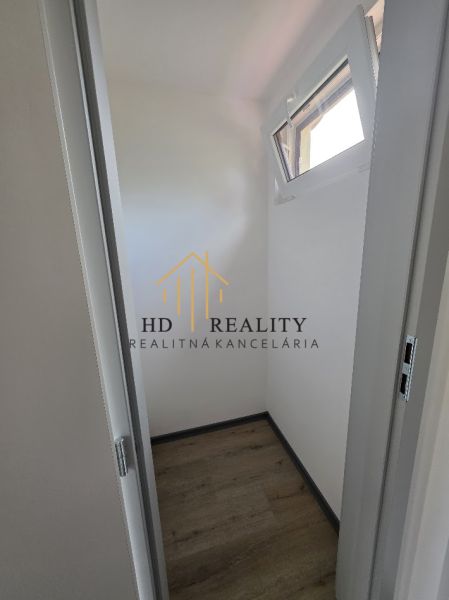 A small room in a cabin with a wooden decor floor and a narrow window.