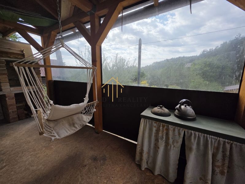 Hanging chair and table with kettles in a cottage with a view of the surroundings.