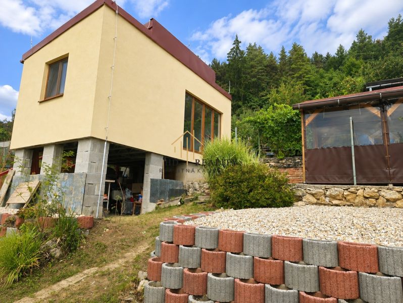 A cottage on Tulská Street in Banská Bystrica surrounded by greenery and stones.