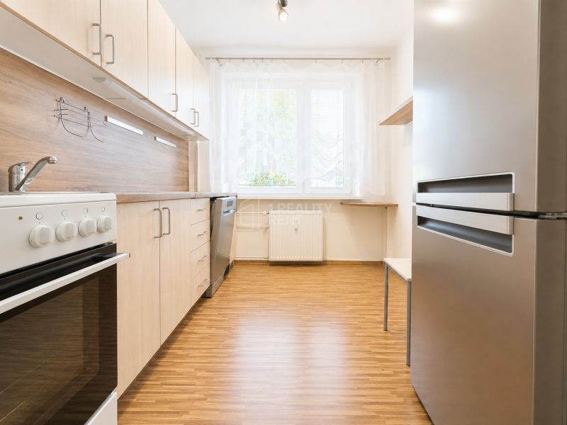 A kitchen in a 3-room apartment with a wooden decor, stove, and refrigerator.