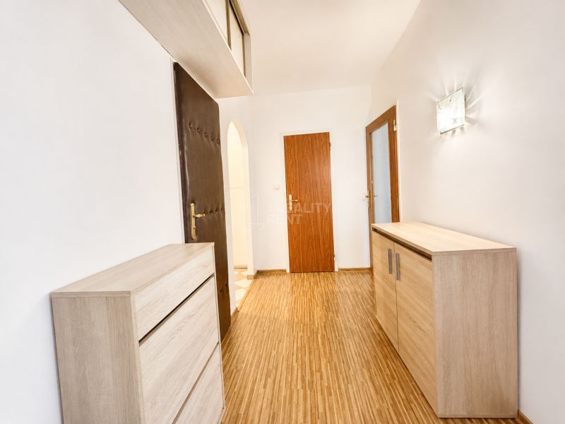A hallway with a wood-decor floor and furniture in a 3-room apartment.