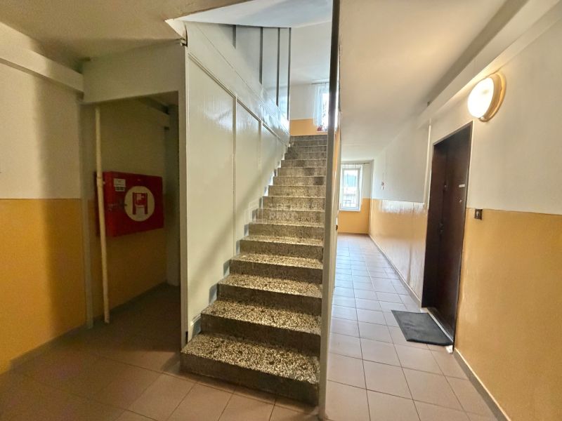 A corridor with interior stairs and doors leading to a 3-room apartment.