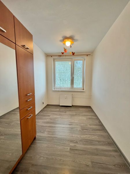 A room with a wooden decor floor and a built-in wardrobe in a 3-room apartment.