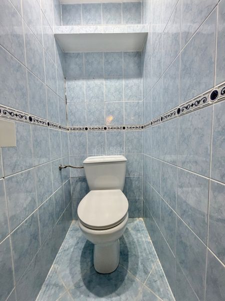 A bathroom with blue tiles in a 3-room apartment with storage space.