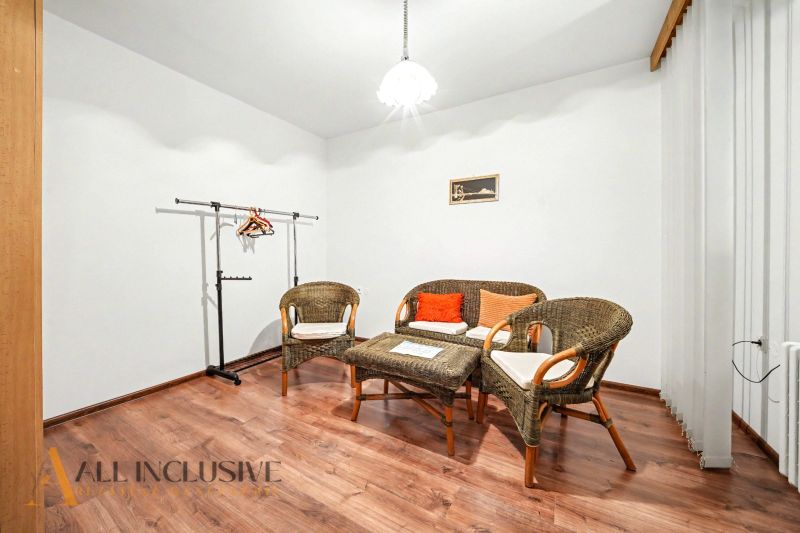 In the family house, there are rattan chairs, a table, and a floor with a wooden decor.