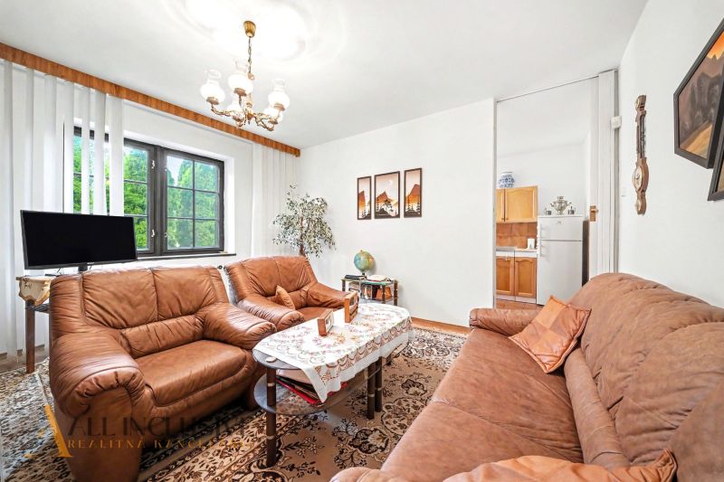 Living room in a family house with brown sofas and a floral patterned carpet.