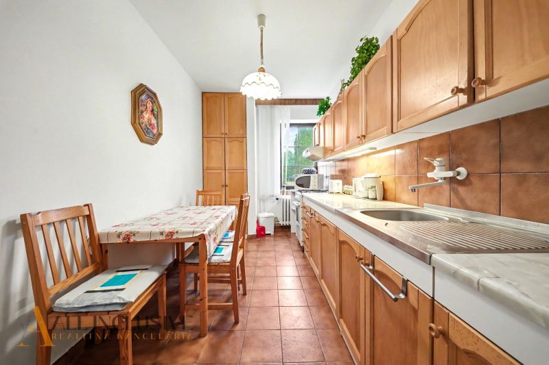A kitchen in a family house with a long table, wooden chairs, and wooden cabinets.