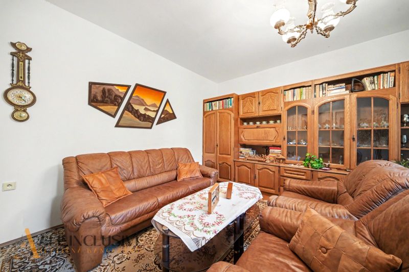A living room in a family house with a brown sofa and wooden furniture.