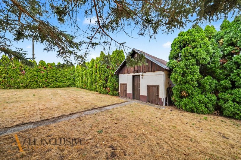The courtyard of a family house in Lipov with a wooden structure, surrounded by a dense hedge.