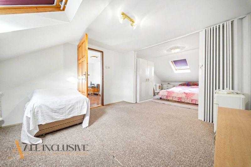 The attic of a family house with skylights, beds, and wardrobes.