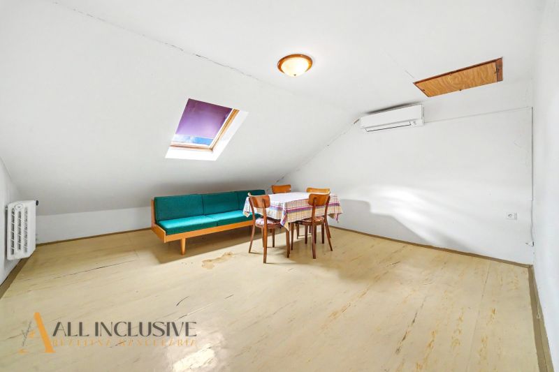 Interior of a family house with a sofa, table, chairs, and a window in the attic.