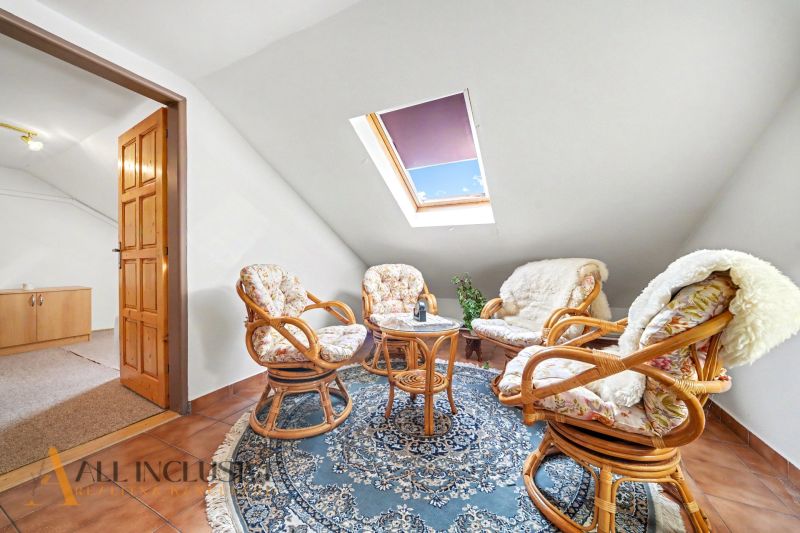 Attic room of a family house with four armchairs, a table, and a blue carpet.