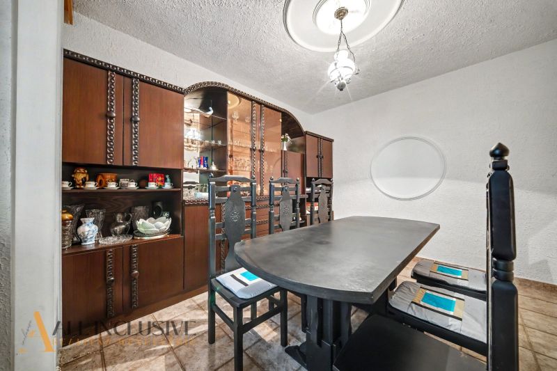Dining room with a wooden sideboard and a dark table in a family house.