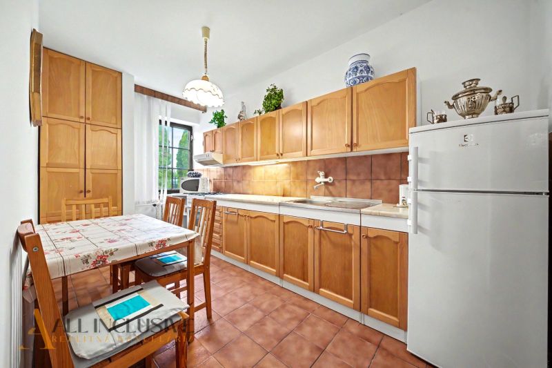 A kitchen in a family house with wooden cabinets and a dining table.