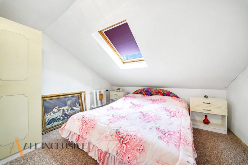 Attic room in a family house with a bed, a skylight, and a painting leaning against the wall.