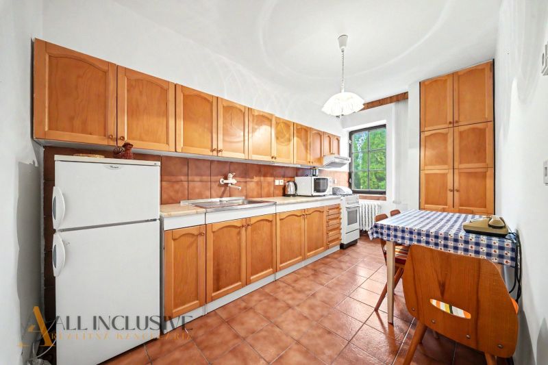 Family house kitchen with wooden cabinets, refrigerator, and dining table.