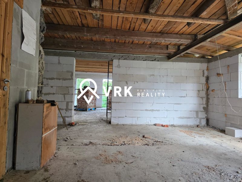 Interior with a view of the unfinished walls and wooden ceiling of a family house.