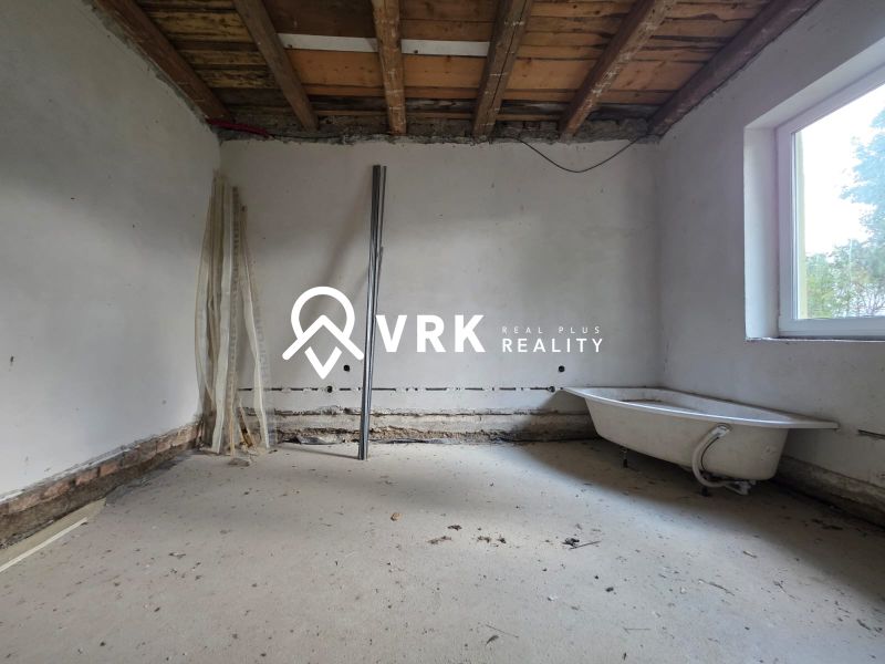 Interior of a family house under construction, with incomplete flooring and a bathtub.