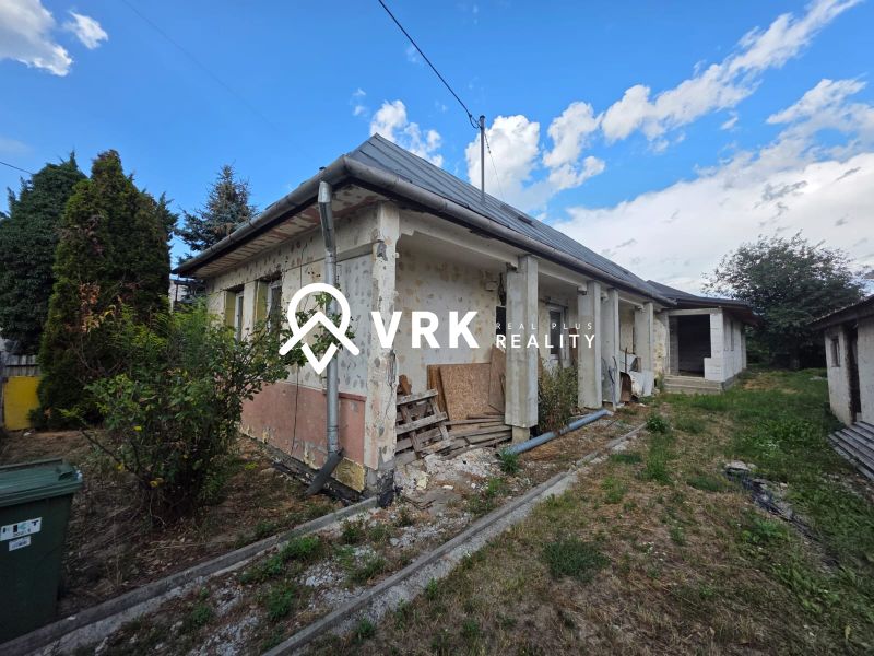A family house in Kokšov-Bakša with windows, a garden, and a blue sky in the background.