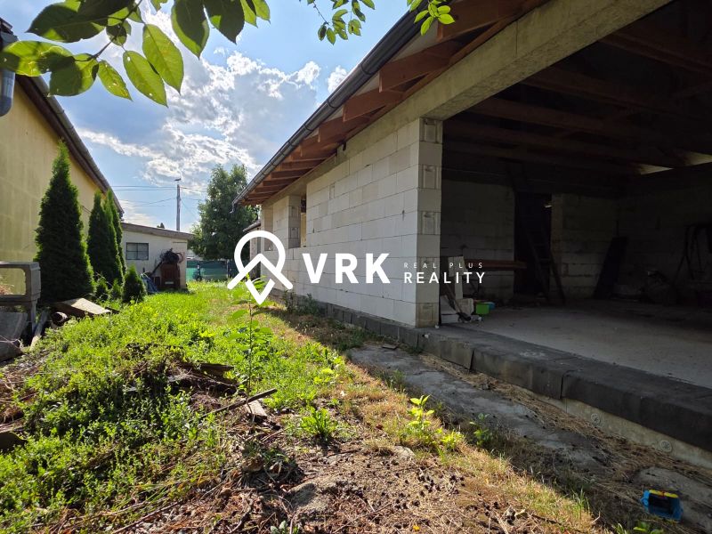 A family house in Kokšov-Bakša with a garden and an outdoor building on a summer day.