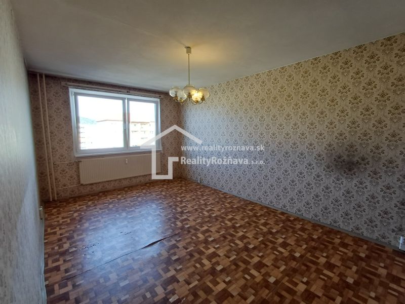 A room with wallpaper and a wooden decor floor in a studio apartment.