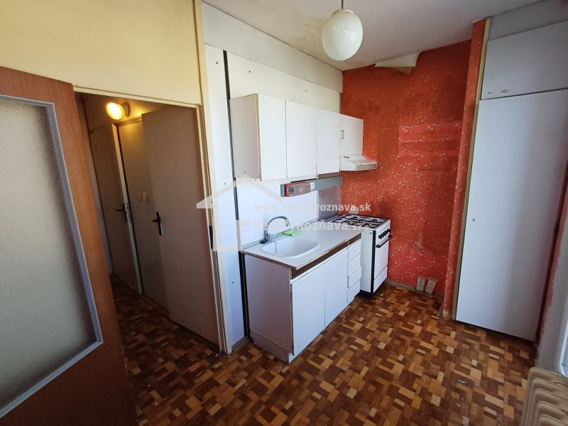 Compact kitchen in a studio apartment with a wooden decor floor and a simple kitchenette.