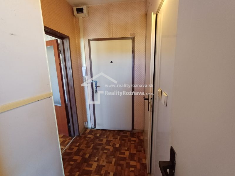 Entrance hallway with wood-patterned flooring in a studio apartment, walls with patterned wallpaper.
