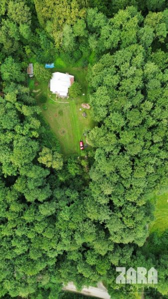 Aerial view of a cabin surrounded by dense forest in Šugovská Valley, Medzev.