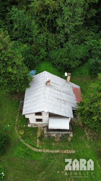 A cottage surrounded by trees in the Šugov Valley in Medzev with a grassy plot.