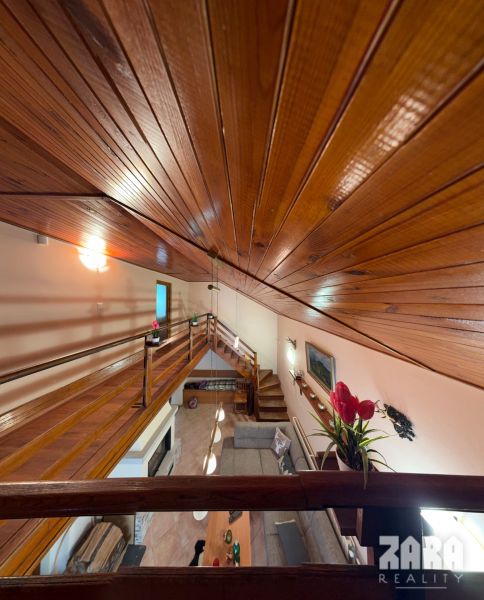 A cabin with a wooden ceiling and floor, view from the gallery to the living room.