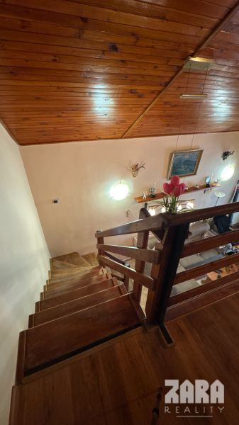 Stairs leading to the living room in a cabin with wooden decor on the ceiling.
