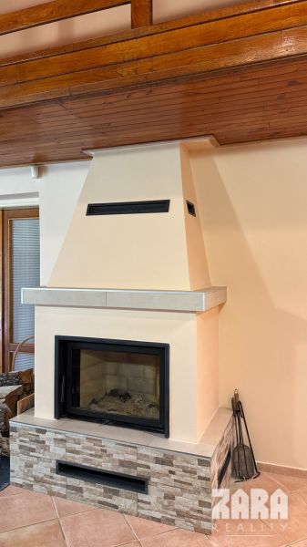 Fireplace in a cabin with a wooden ceiling and stone cladding.