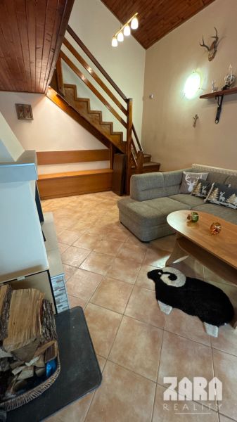 Interior of a cabin with a wooden staircase, a sofa, and a decorative sheep rug.