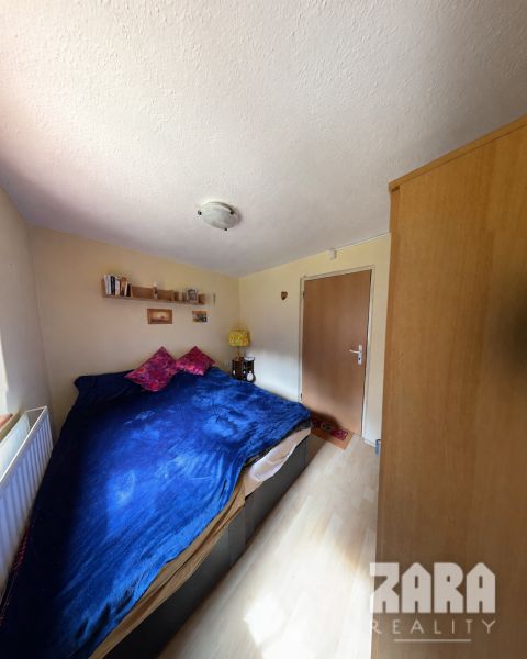 Room in a cottage with a bed, decorated floor, warm lighting, and furniture.