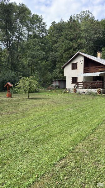 A cottage in the Šugov Valley near Medzev, surrounded by meadows and forests, with a wooden terrace.