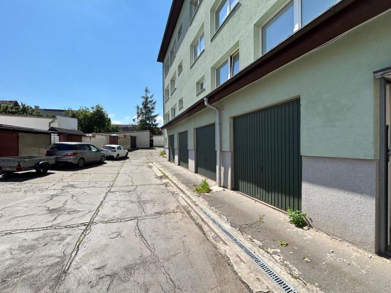 Parking lot in front of the offices in Kežmarok, next to the building with green garage doors.