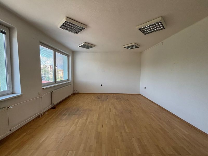 A spacious office with a wooden decor floor and large windows.