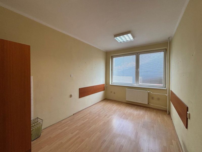 An office with large windows, wooden decor flooring, central heating.