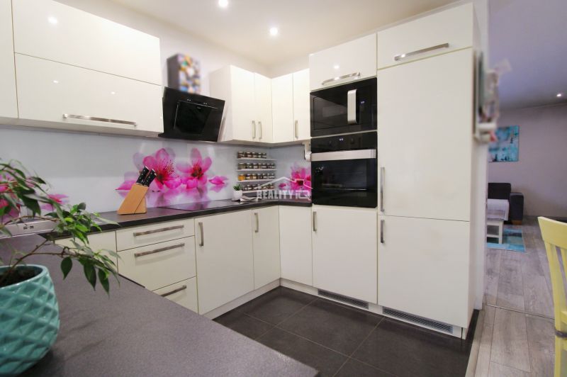 Corner kitchen in a family house with flower decor on the wall and storage space.