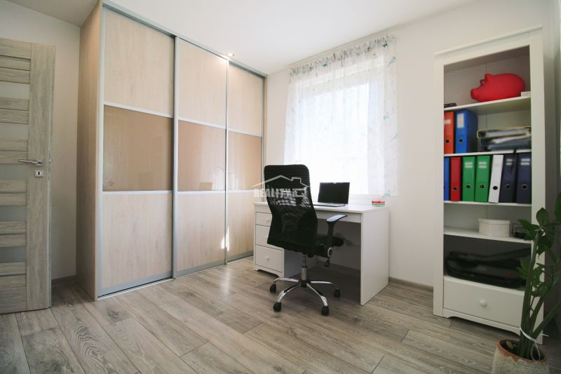 Interior of a family house with a wooden decor floor, a desk, and a wardrobe.