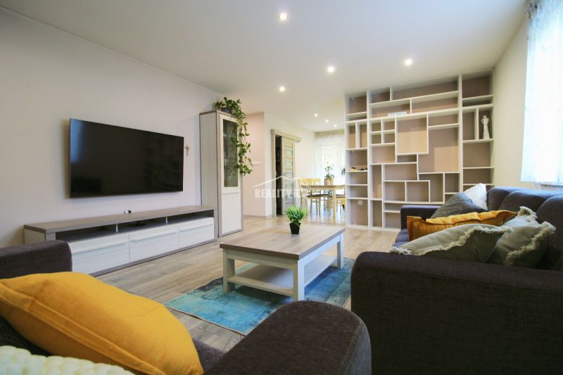 Living room in a family house with a wood-patterned floor and a large TV screen.