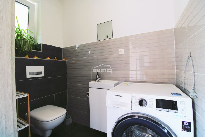 A bathroom with a washing machine and toilet in a family house, a simple and practical solution.